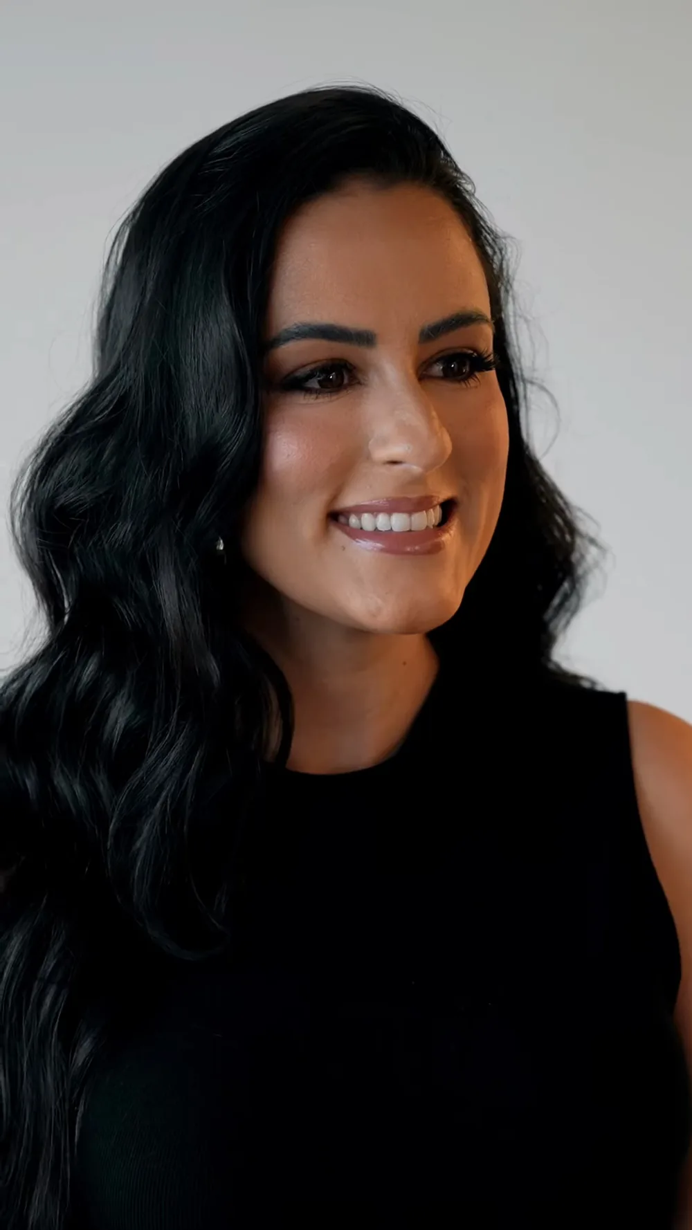 Dra. Mallu Cerutti de blusa preta, cabelo solto, sorrindo